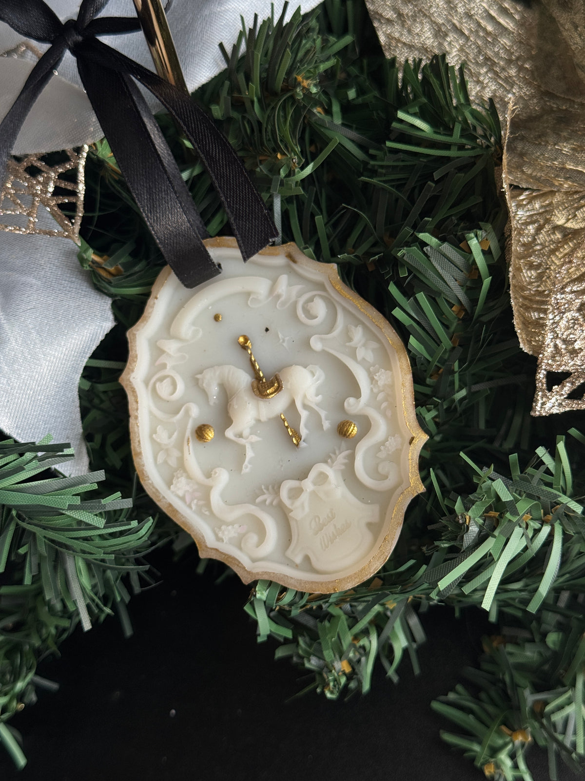 The Heirloom Carousel, an ivory olive wax rocking horse keepsake with gold detail and a black satin ribbon