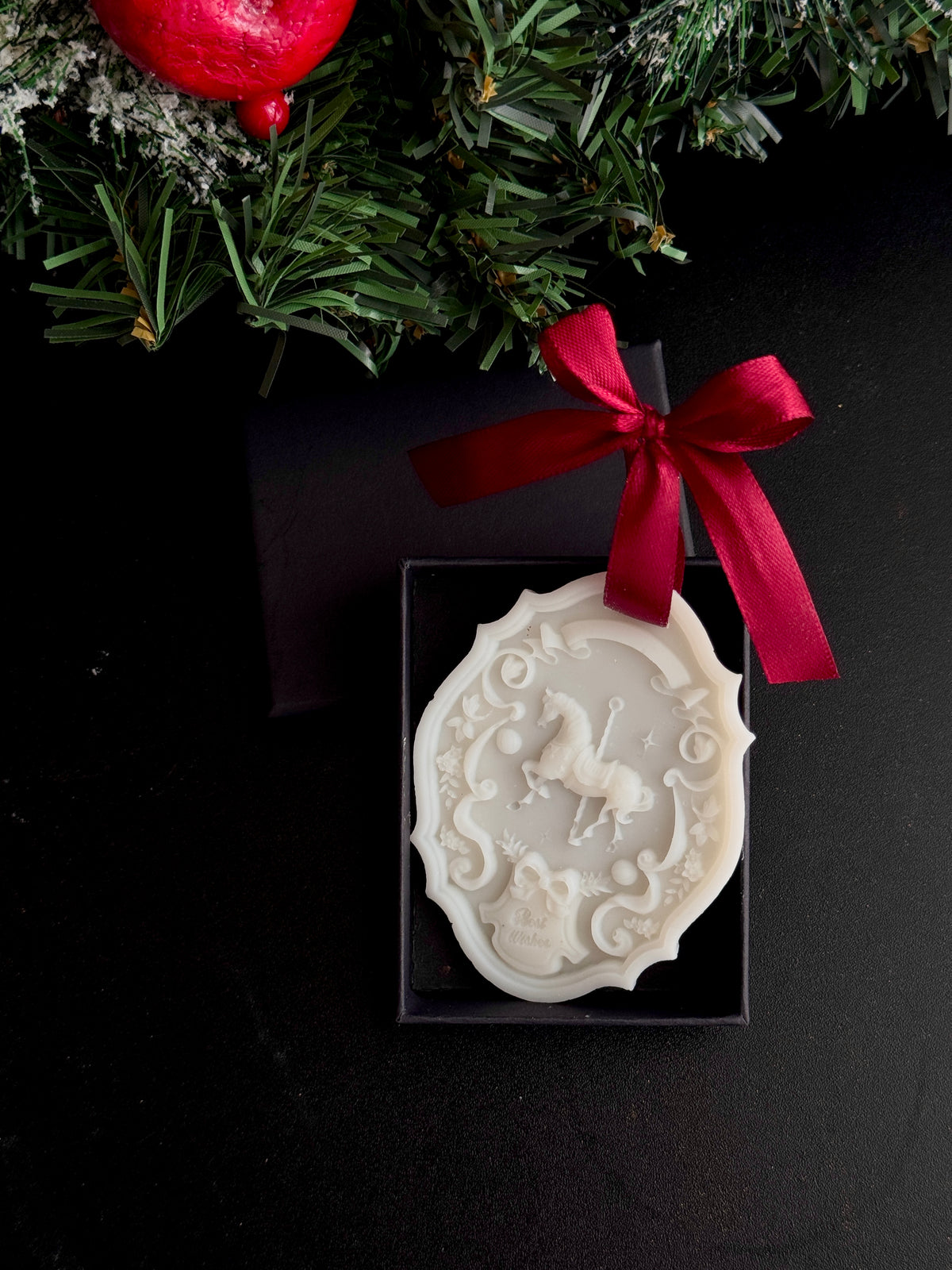 The Heirloom Carousel, an ivory olive wax rocking horse keepsake with gold detail and a black satin ribbon