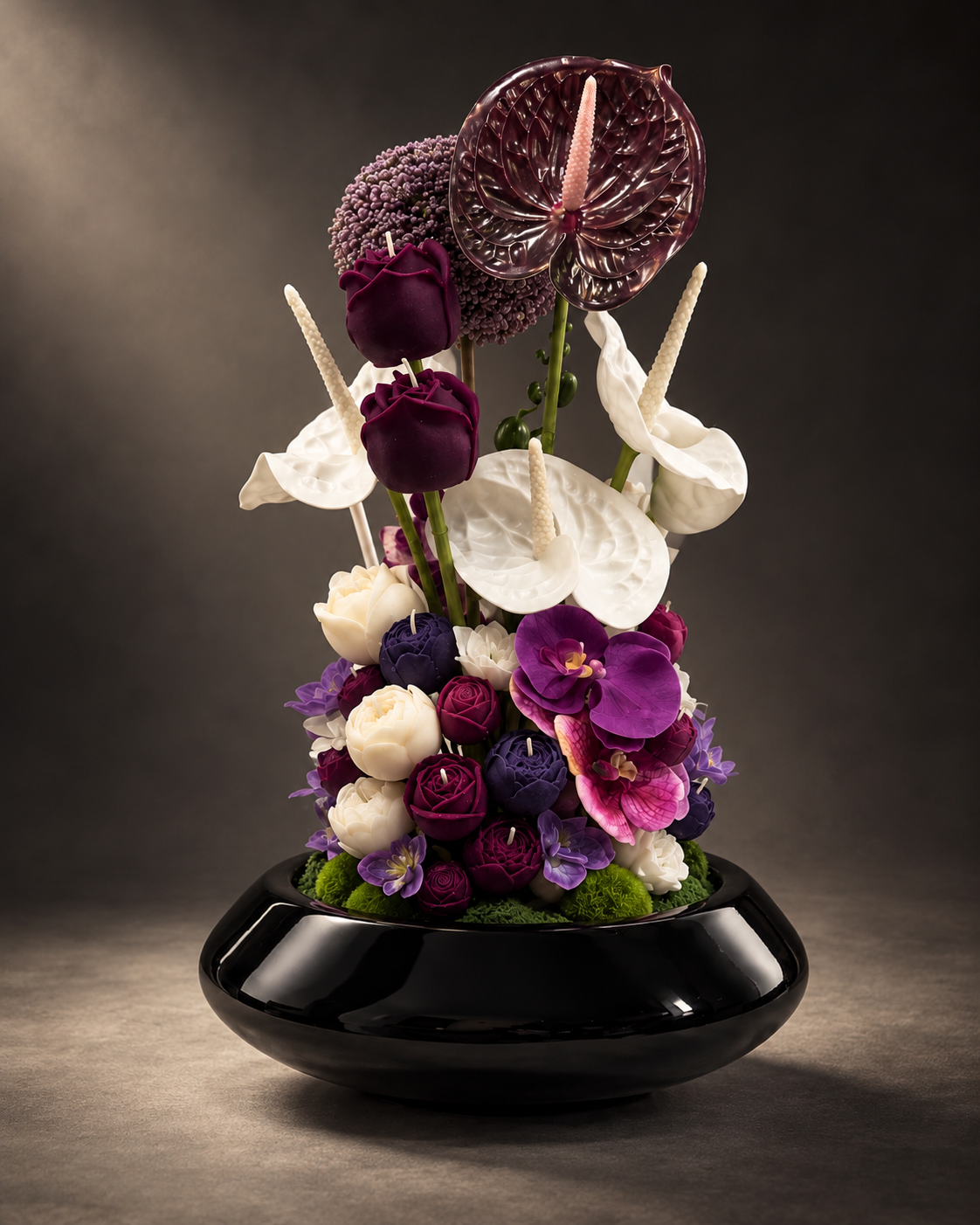 Amarante, a candle bouquet of burgundy, plum and ivory wax roses, anthuriums and orchids in a glossy black bowl